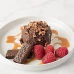 On a white plate with fresh raspberries and caramel sauce