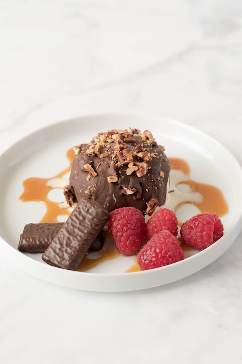 On a white plate with fresh raspberries and caramel sauce