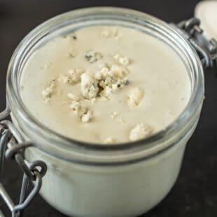 A closeup showing blue cheese crumbles in salad dressing