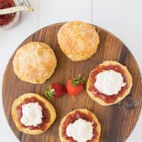 A round board of scones with jam and cream
