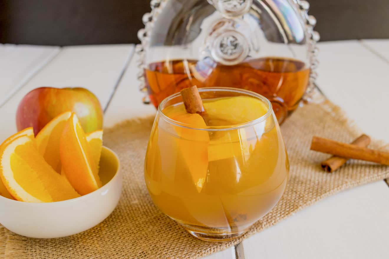 Orange wedges in a bowl and also in a cognac apple cocktail in a glass
