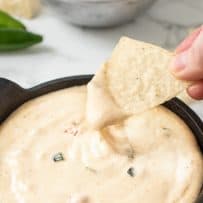 Creamy queso dripping off a tortilla chip
