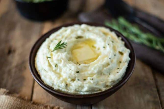 A brown bowl filled with creamy rosemary cauliflower mash