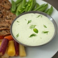 A closeup of the dipping sauce garnished with fresh dill and mint
