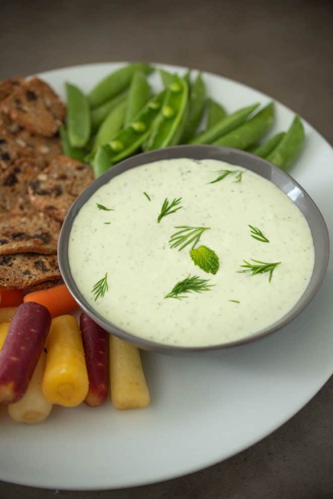 A closeup of the dipping sauce garnished with fresh dill and mint