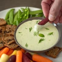 Dipping a carrot into creamy tzatziki dipping sauce