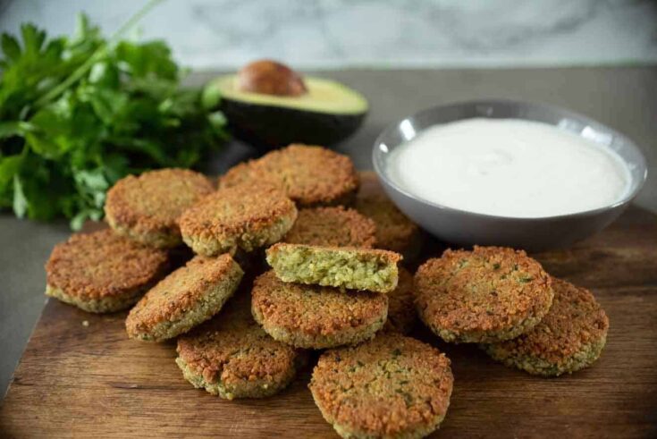 Brown and crispy falafel on a serving board with yogurt tahini sauce