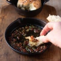 Dipping a piece of bread roll into bacon sage butter