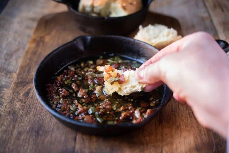 Dipping a piece of bread in to crispy bacon and sage in melted butter
