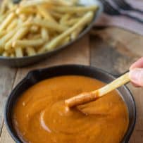 Dipping a French fry into a bowl of curry sauce