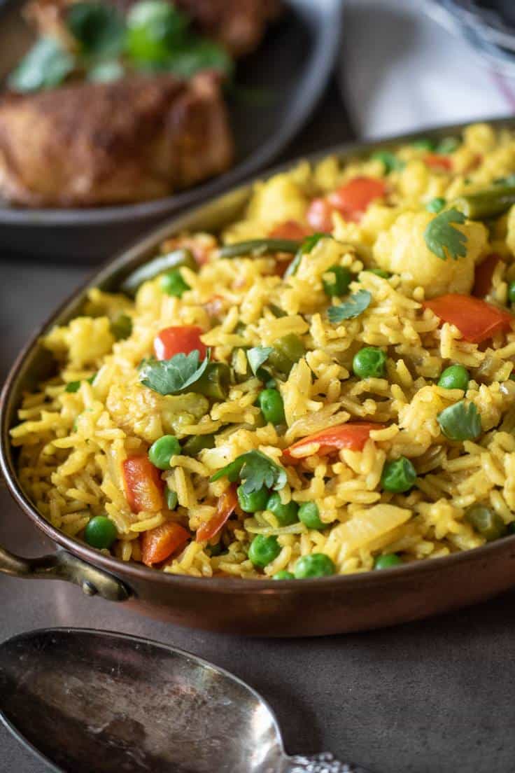 A closeup showing the beautiful yellow rice with the green peas and red peppers