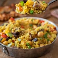A spoonful of curry quinoa with mushrooms, peas, carrots and raisins