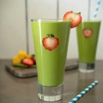 Strawberry slices on the inside of the glass and on the rim of this detox green smoothie