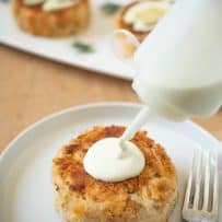 Squeezing lemon scallion sauce onto a crab cake