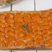 Vibrant orange slices of apricot on top of a puff pastry crust