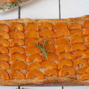 Vibrant orange slices of apricot on top of a puff pastry crust