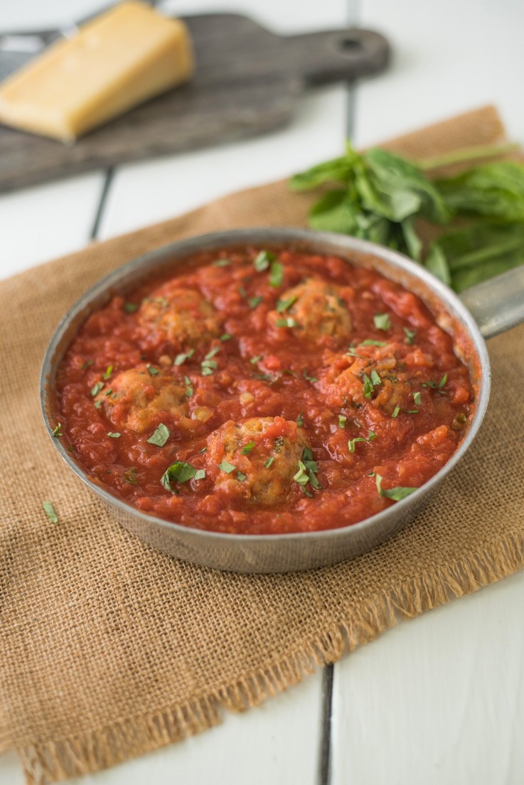 A pan of easy chicken meatballs in marinara sauce garnished with fresh basil
