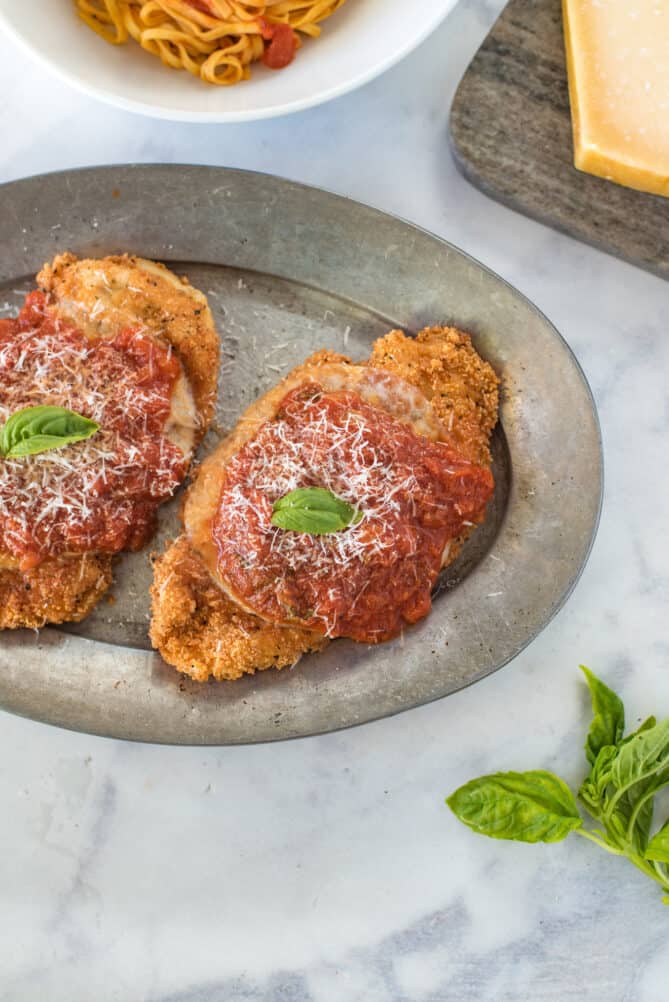 An overhead of chicken Parmigiana on an oval plate