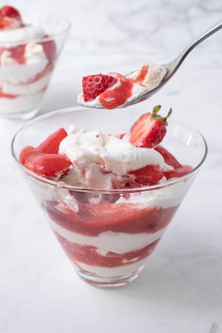 Meringue, strawberry and whipped cream on a spoon
