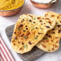 Browned naan bread garnished with cilantro