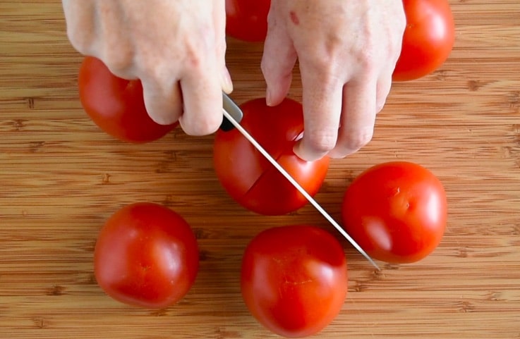 The skin of fresh tomatoes is scored with an X