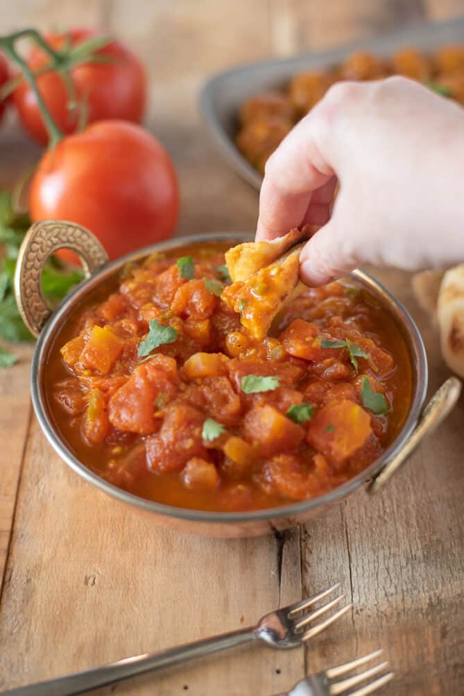 Dipping a piece of naan bread into Indian tomato chutney