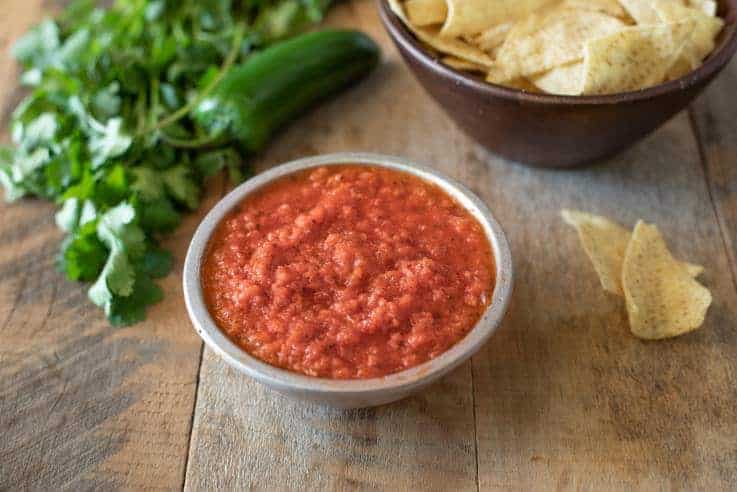 A bowl of Easy Restaurant-Style Red Salsa with cilantro and tortilla chips