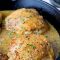 Dijon sauce in a pan cooking with chicken thighs garnished with green parsley