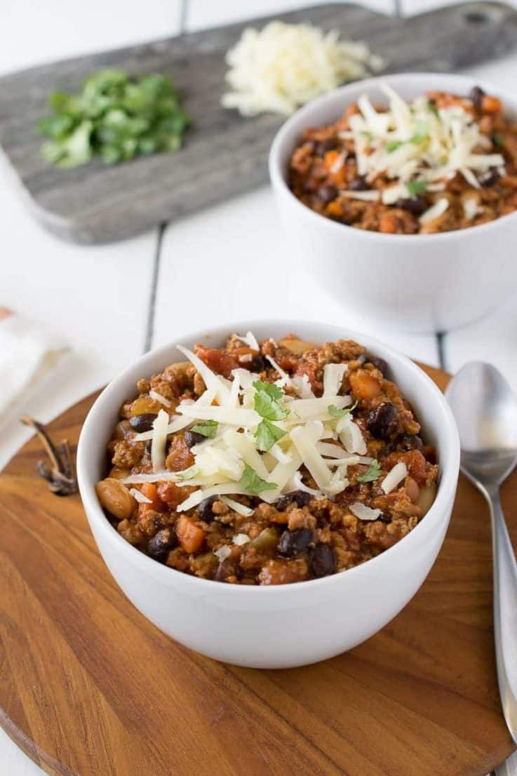 Turkey chili in a white bowl topped with grated cheese and cilantro