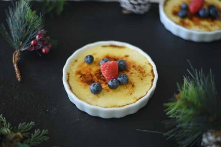 A ramekin filled with eggnog creme br&ucirc;l&eacute;e, raspberry and blueberries