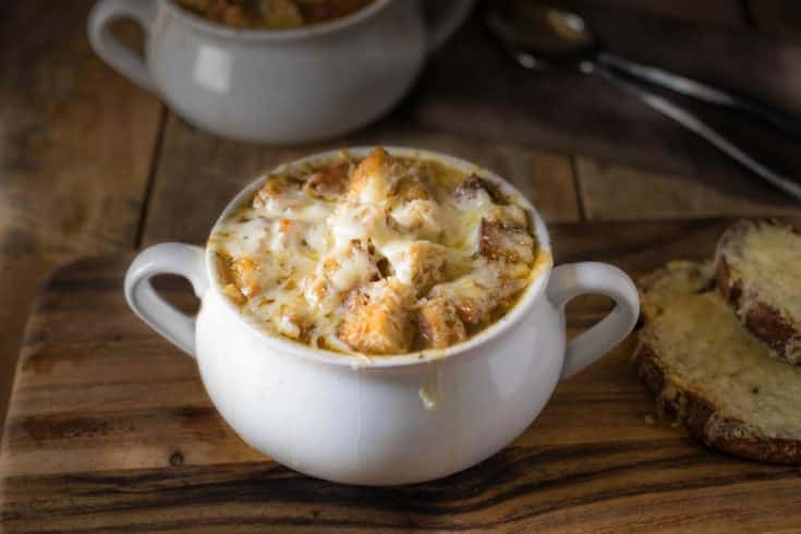 French onion soup in a white bowl with a side of cheese toast