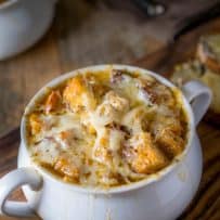 A crock-style soup bowl filled with French onion soup, topped with croutons and melted cheese