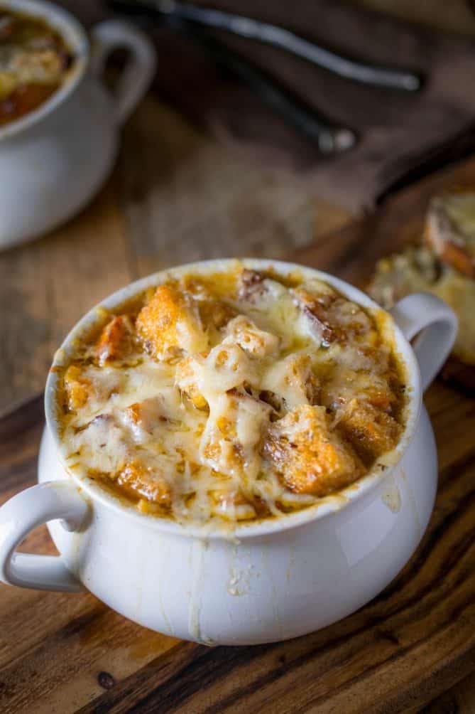 A crock-style soup bowl filled with French onion soup, topped with croutons and melted cheese