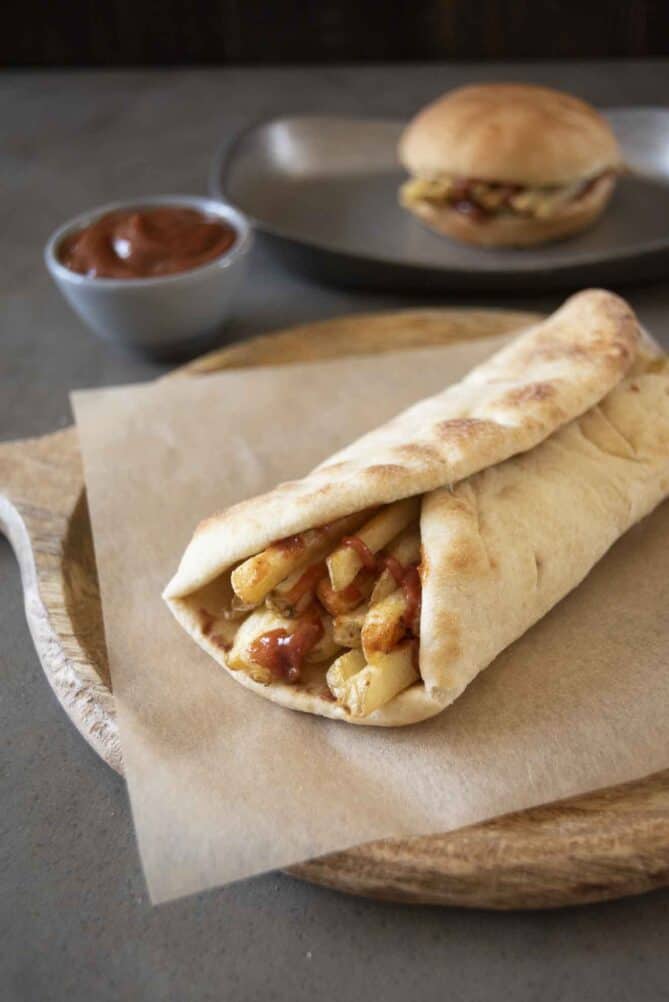 Crispy French fries stack on top of each other drizzled with ketchup wrapped in naan bread