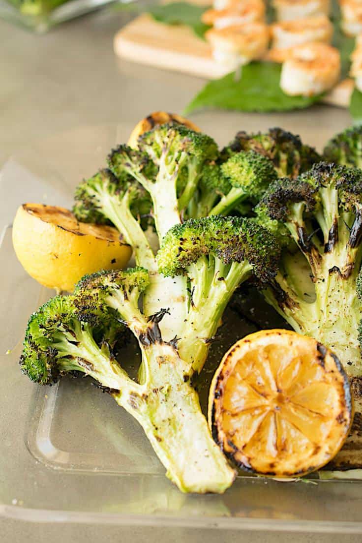 A closeup of grilled broccoli with a half of lemon