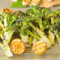 Grilled broccoli with lemon slices on a serving board