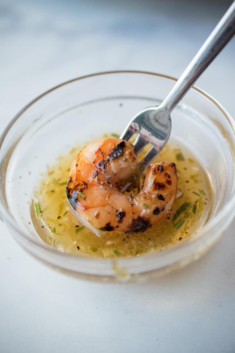 A perfectly grilled shrimp getting dipped into a key lime sauce