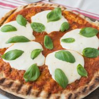 Perfect grill marks on the crust of this pizza with sauce, mozzarella and basil