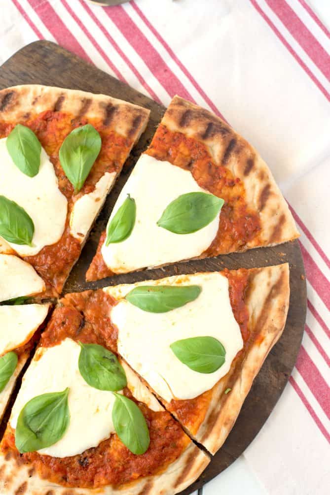 The pizza sliced with garnished with whole basil leaves