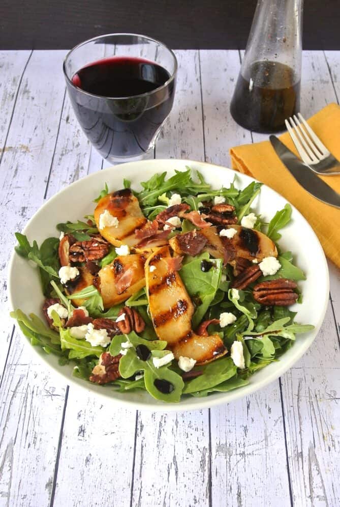 Arugula salad topped with baked pear, pecans, goat cheese and crispy prosciutto