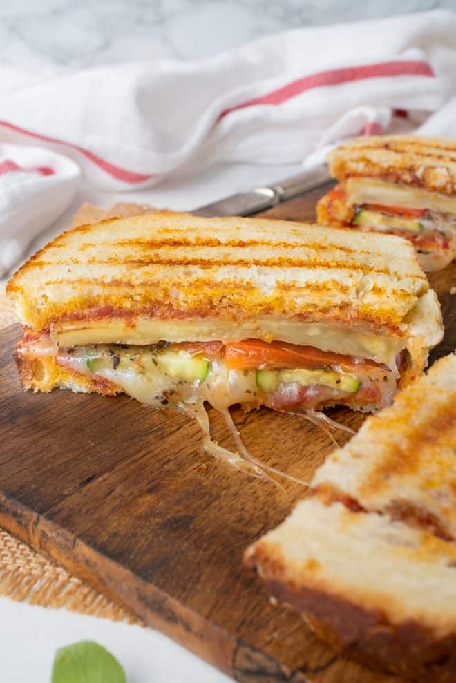 Grilled summer vegetable panini on a cutting board cut in half