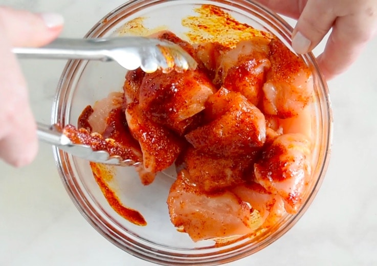 Chicken breast pieces getting coated with spices
