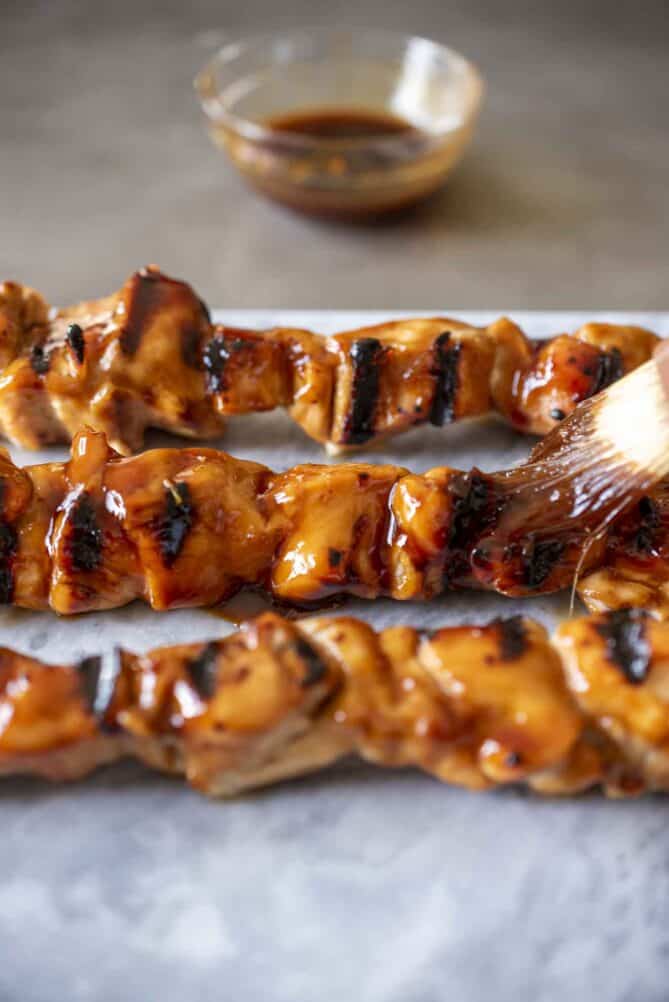 Brushing teriyaki sauce over grilled chicken