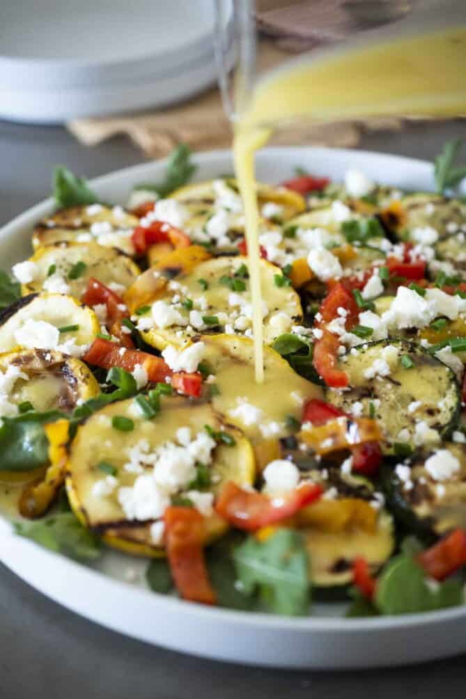 Drizzling Dijon vinaigrette over grilled zucchini