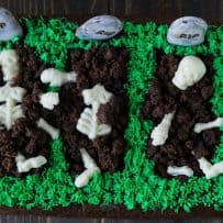 3 graves cut out of a brownie with white chocolate skeletons buried