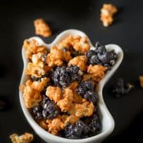 A white bowl in the shape of a ghost filled with orange and black popcorn