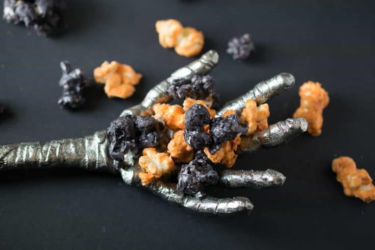 A spooky mummy hand holding Halloween popcorn
