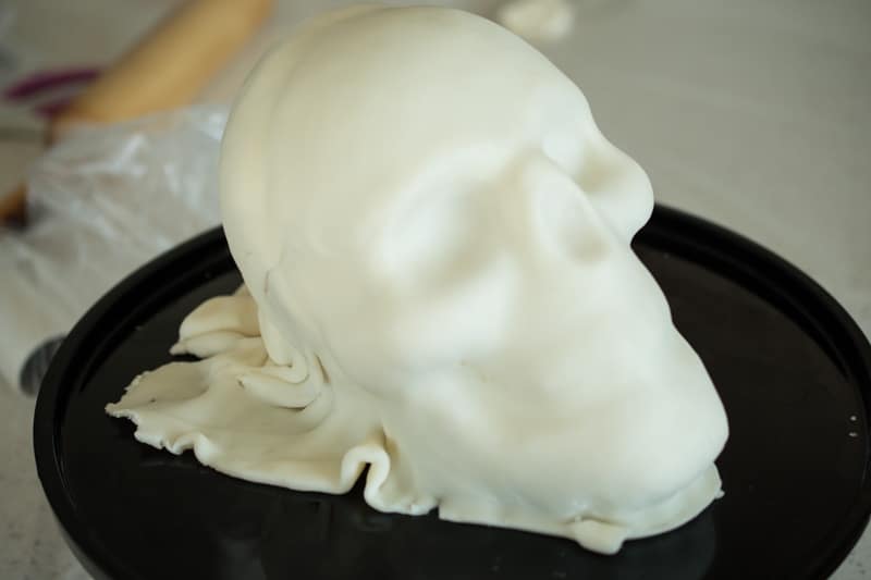 A skull cake being made, covered in white fondant