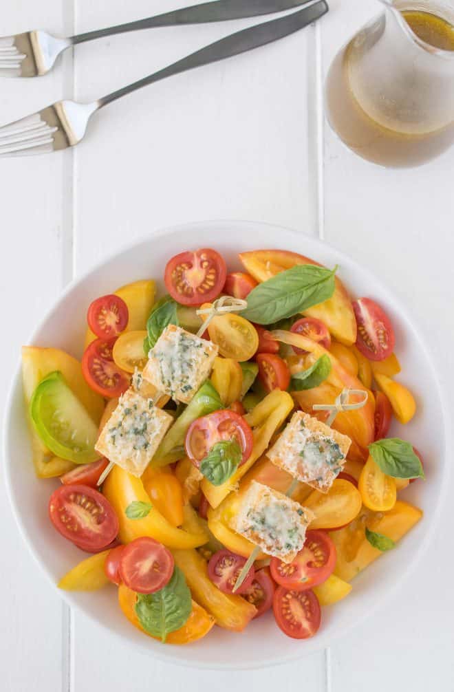 An overhead view of the salad with 2 forks and dressing in a jug