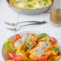 Red and yellow heirloom tomatoes in a bowl topped with Parmesan basil croutons